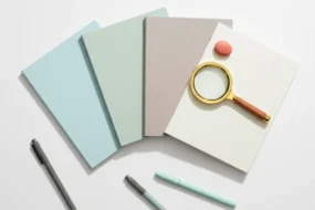 Plain notebooks, pens, and magnifying glass arranged for choosing best free AI detector tools.