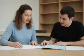 University writing instructor and student reviewing blank paper stacks in an academic office while discussing Turnitin AI detection reliability.