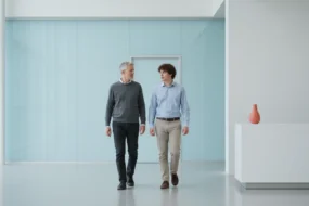 Educator and student walking through a calm pale blue campus space while discussing GPTZero and AI writing review.