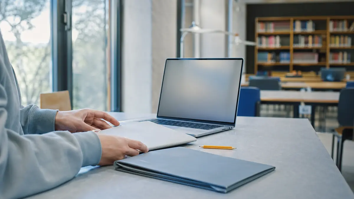Student arranging plain folders beside a blank laptop while locating a Turnitin AI score report.